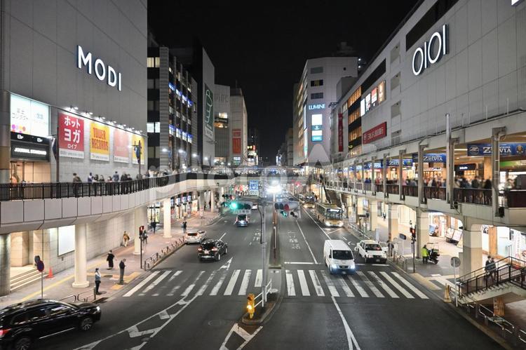 町田駅前の夜景。灯りのともる商業施設と歩道橋、行き交う車の風景