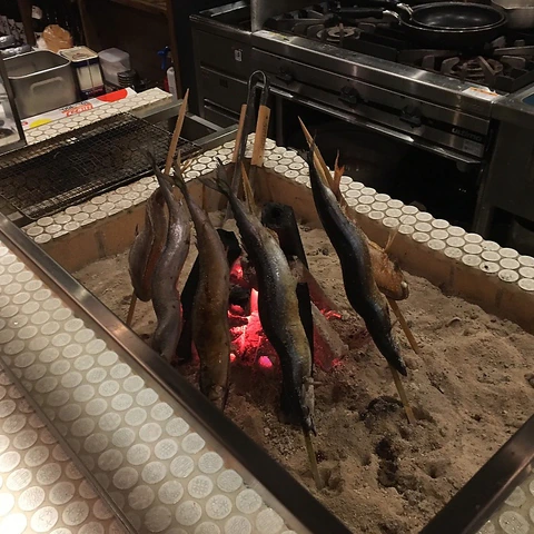 炭火を囲むように串打ちした、囲炉裏の魚